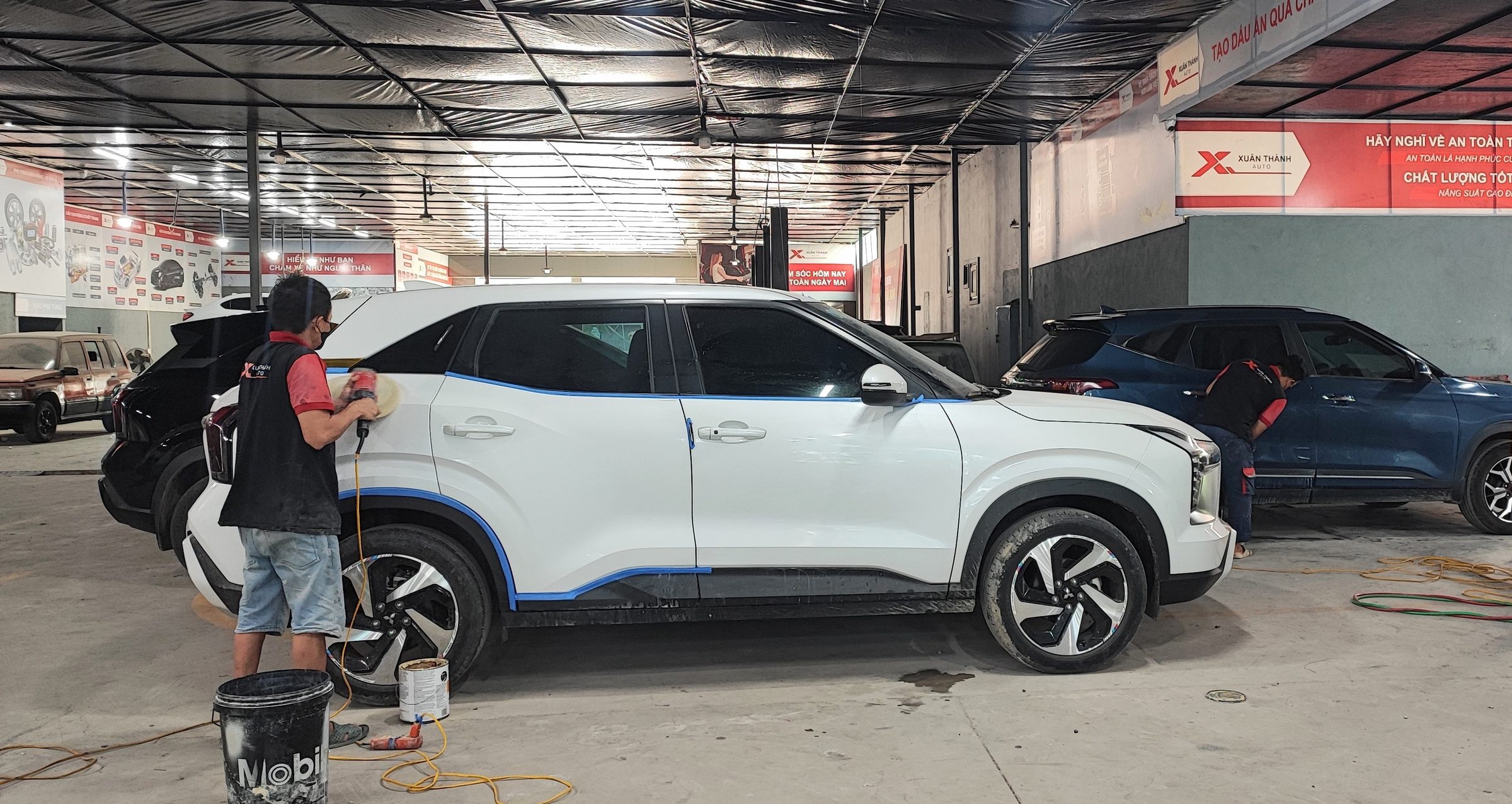 Kỹ thuật viên xử lý bề mặt ngoại thất xe màu trắng tại xưởng